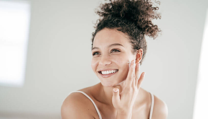 A woman looking in mirror and touching face